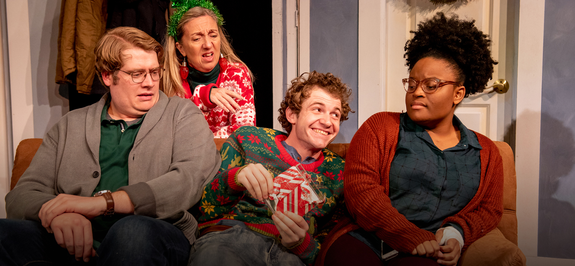 Four people on stage in play; one woman tending to plants