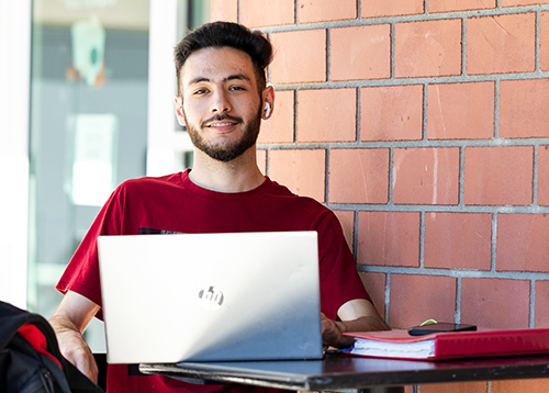 A young gentleman sitting on a table outside with his laptop