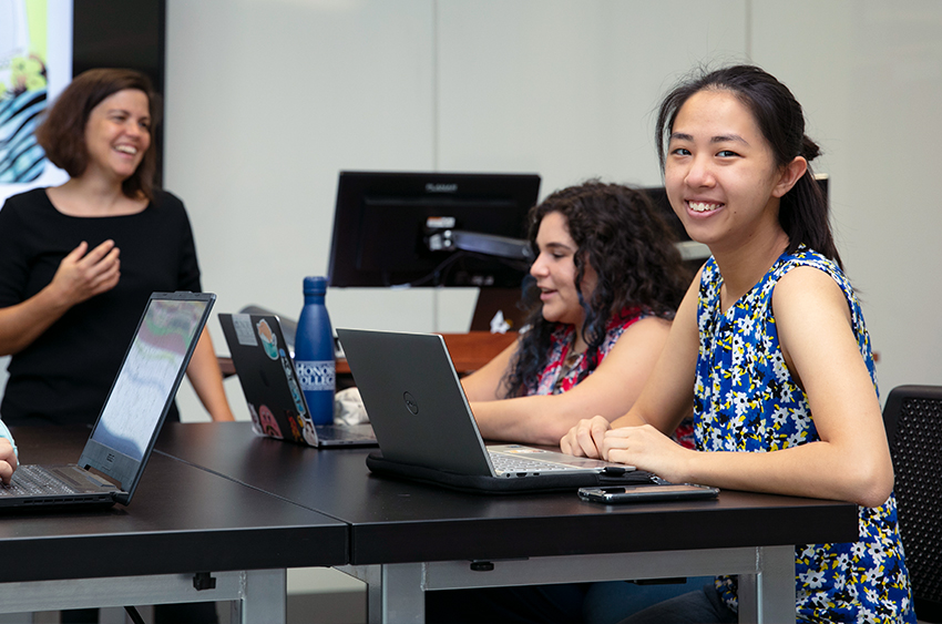 A group of young people sitting at a table with their laptops