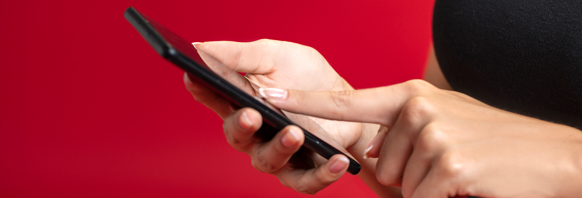 Close-up of hands using a smartphone against a red background.