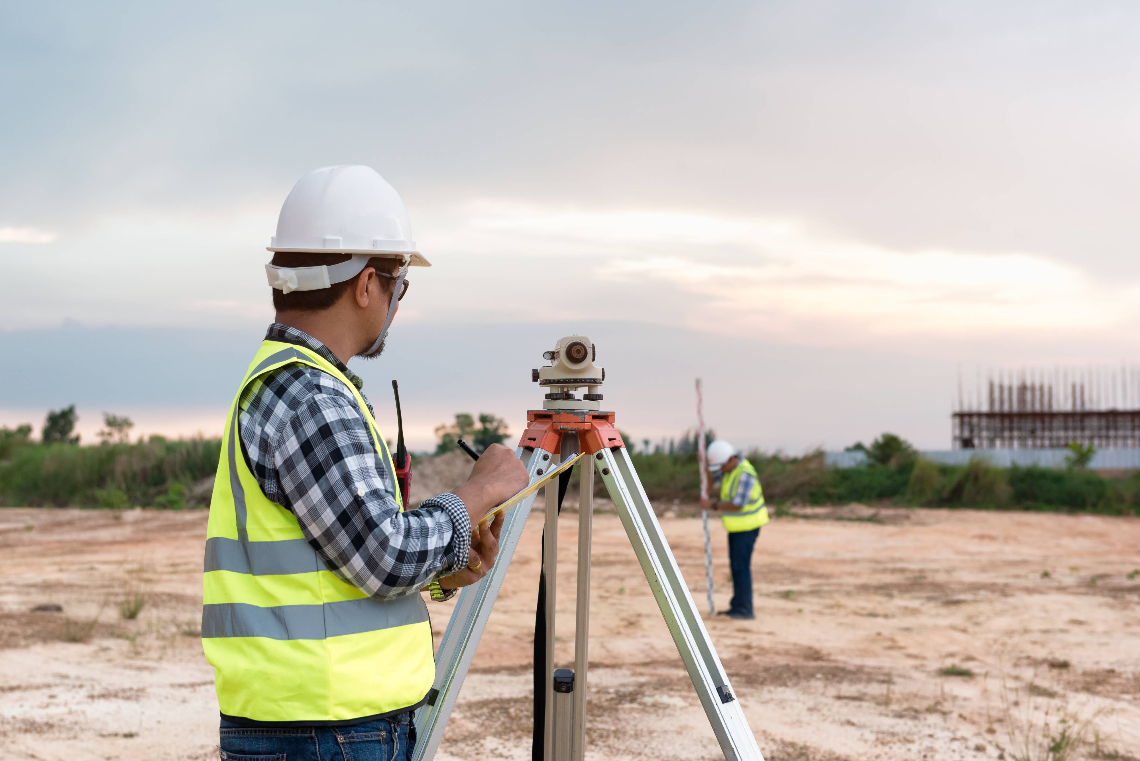 Geomatics Engineering Student with a hard hat looking over at a job site