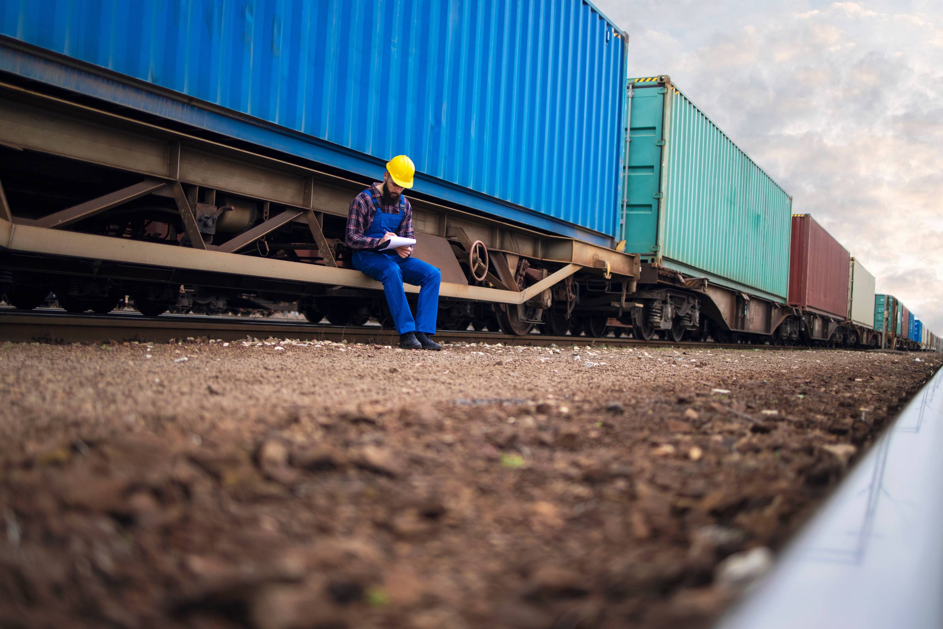Worker with shipping containers and train freight cars
