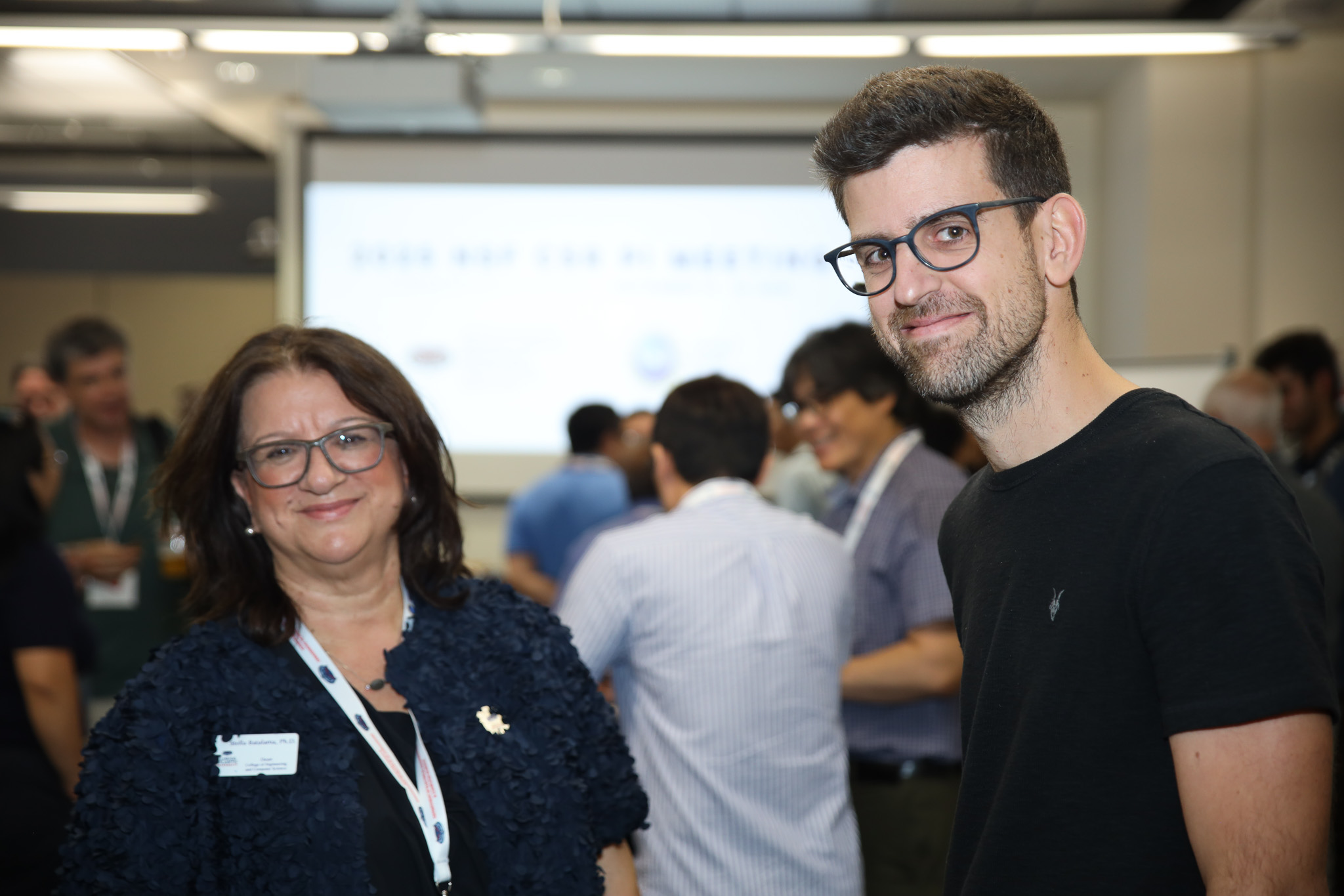 Two people smiling in a presentation room.