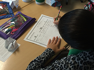 student in classroom setting writing