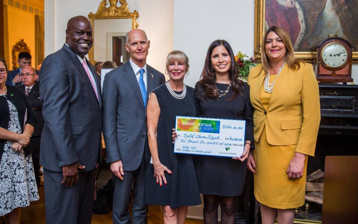 Group of people standing with check and Rick Scott