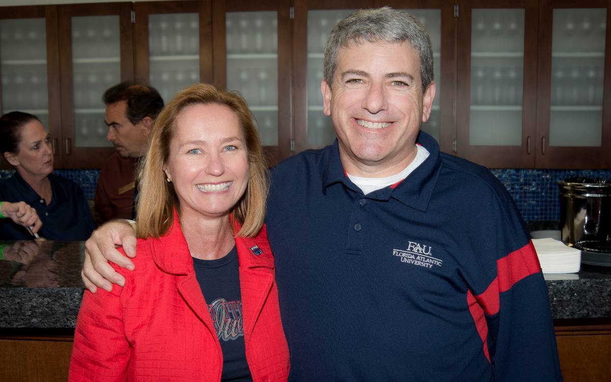 Two men and two women holding up owl signs and smiling