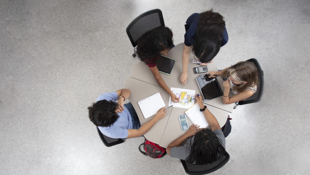 Students sitting around a table using the LA model to learn