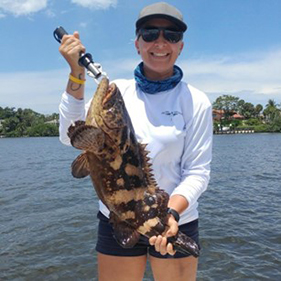 woman holding a fish with ocean in background