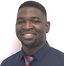 Headshot photo of Rujay Howell, a twenty-something African American male wearing a navy button up shirt with a red plaid tie.