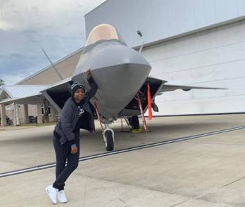 In front of the F-22 fighter jet, which is the aircraft she worked on during her military career